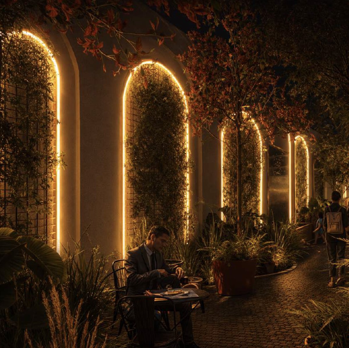 Galería de arcos iluminados con mesas exteriores, vista nocturna